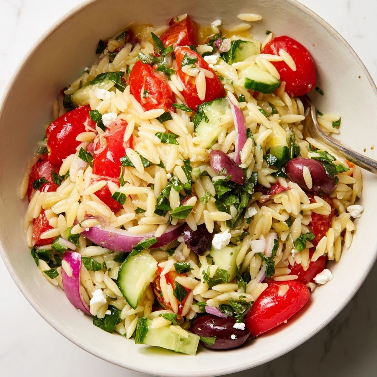 Close-up of a vibrant Mediterranean Orzo Bowl, showcasing colorful vegetables and creamy feta.