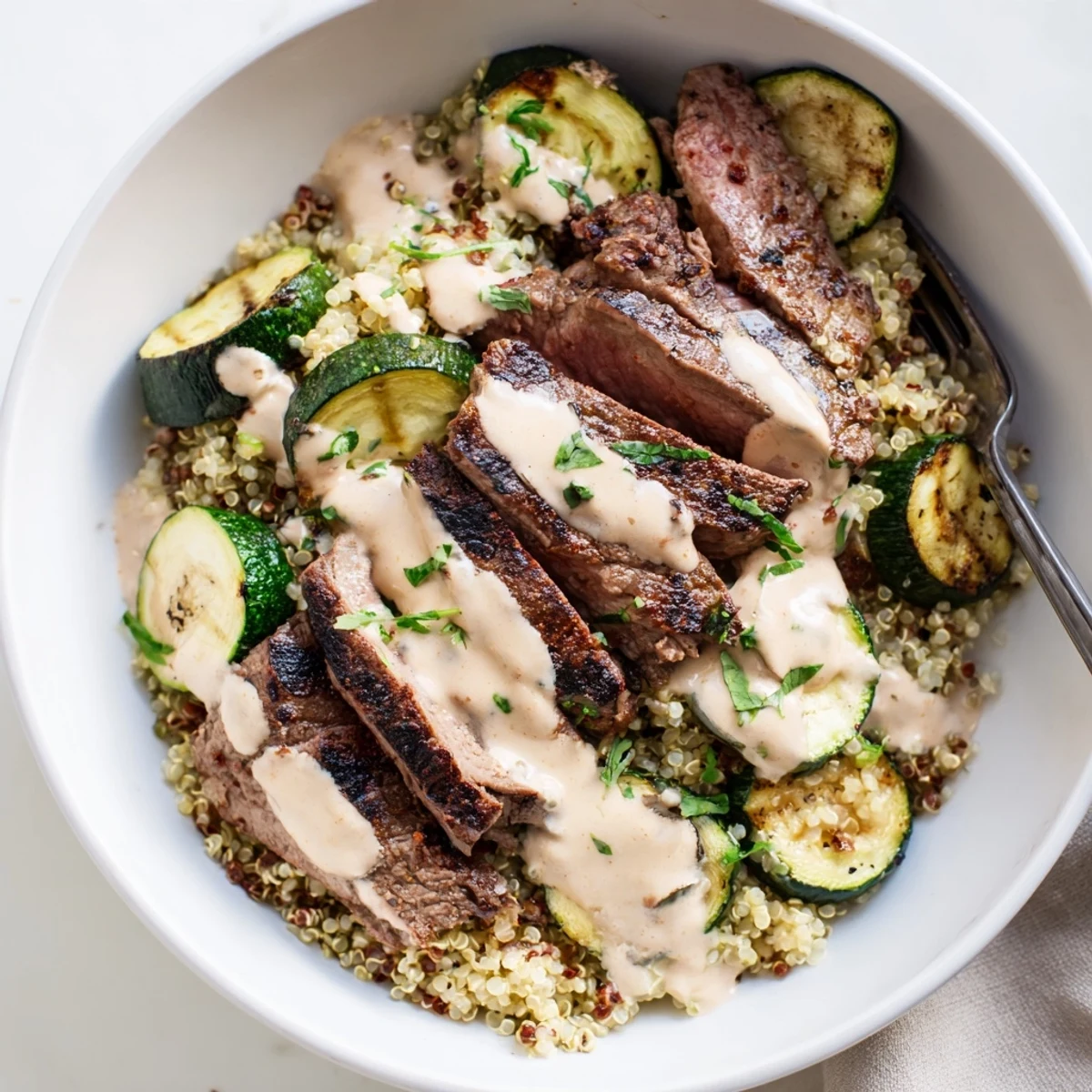 Savory Grilled Steak Bowl with Creamy Sauce and zucchini topped with fresh herbs.  