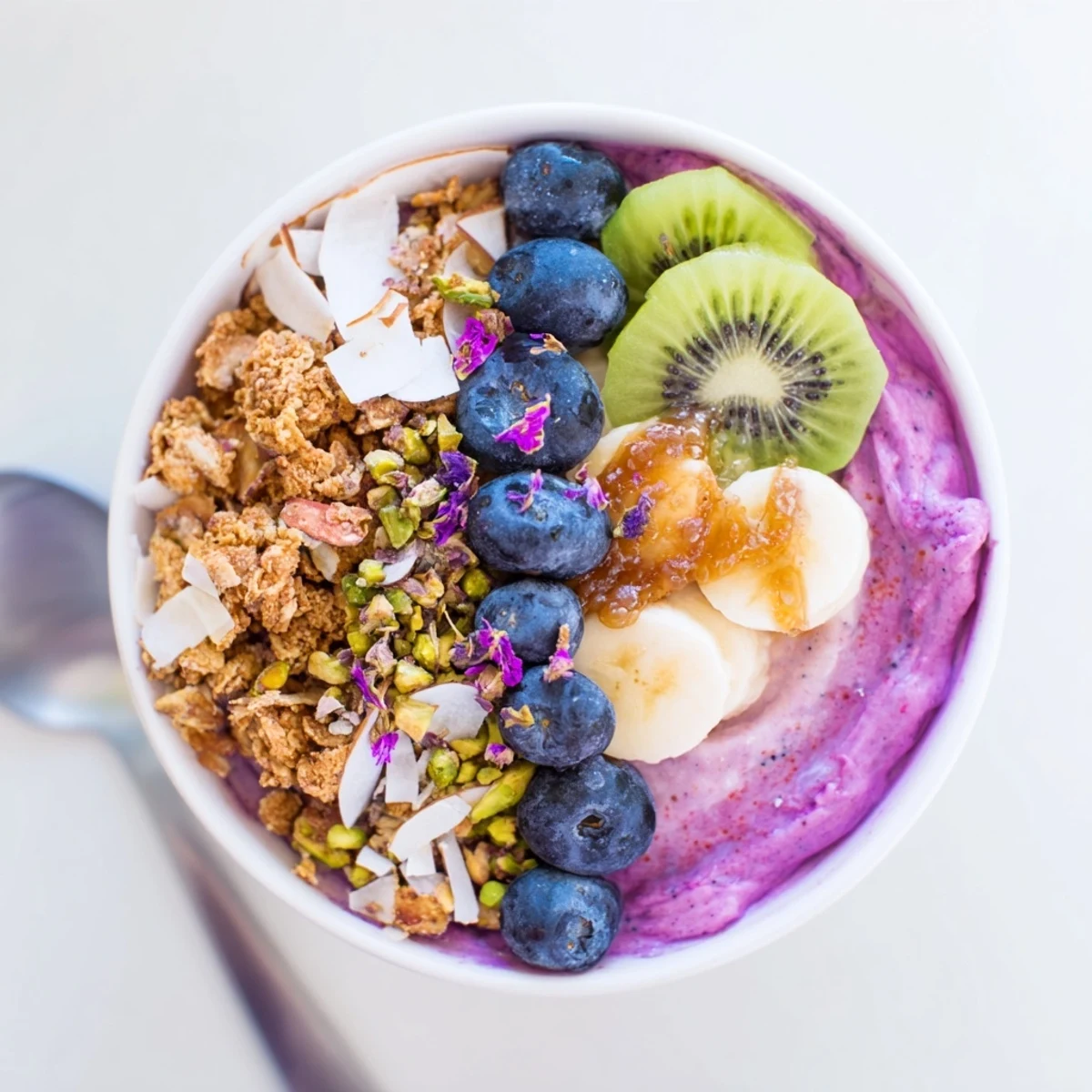 Vibrant smoothie bowls with pistachio and purple yam topped with fresh kiwi slices.  