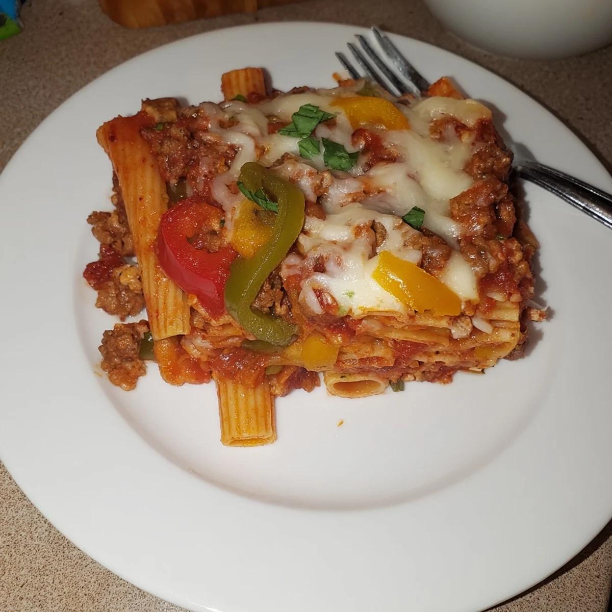 Hearty baked rigatoni with sausage and peppers, topped with melted cheese and herbs.  