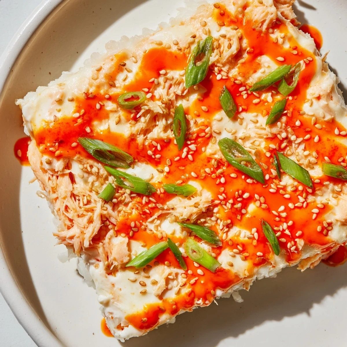 Golden, bubbly Creamy Salmon Sushi Bake, fresh from the oven, with sesame seeds and scallions.