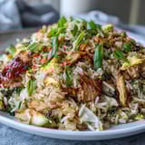 Hot Egg Roll Fried Rice with Chicken is served in a skillet, garnished with green onions and ready for a quick weeknight meal.