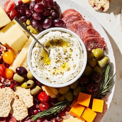 A festive evergreen wreath board overflowing with cheeses, meats, fresh fruits and nuts.