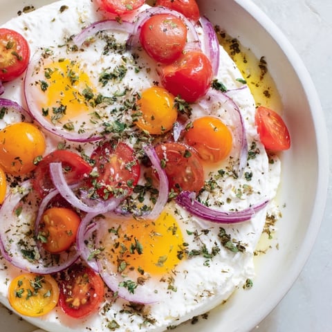 Freshly baked Mediterranean Feta & Eggs featuring a creamy feta block surrounded by vibrant roasted vegetables.