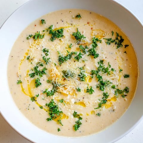 Steaming bowl of creamy garlic bread soup garnished with fresh parsley, ready to eat!