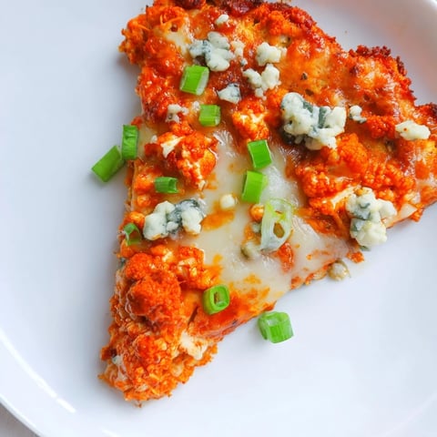 Golden, crispy Buffalo Cauliflower Pizza slices topped with melted mozzarella, spicy red sauce, and fresh green onions on a rustic board.