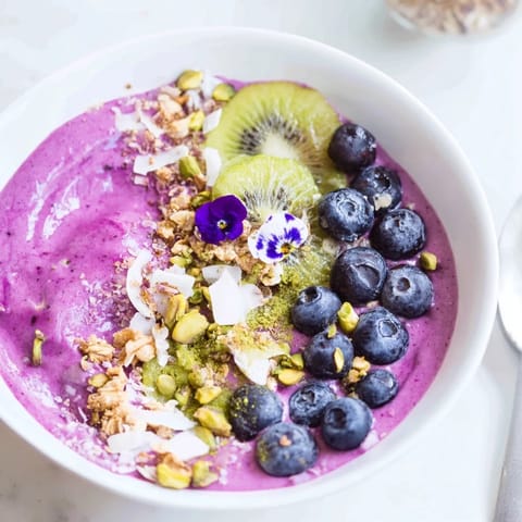 Colorful breakfast smoothie bowls featuring fresh berries and crunchy pistachio toppings.  