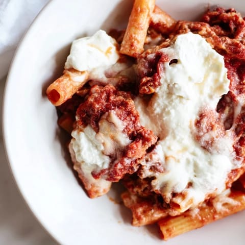 Hot, cheesy slow cooker baked ziti, a close-up of the delicious layers of pasta and sauce.