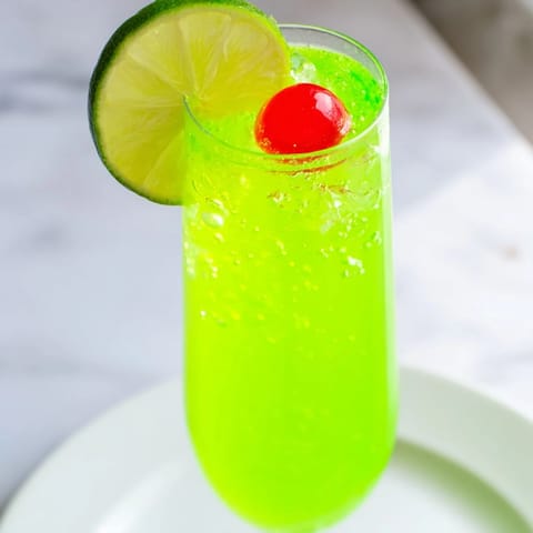 A chilled glass brimming with a vibrant Quick Grinch Mimosa Mocktail, perfect for holiday celebrations.
