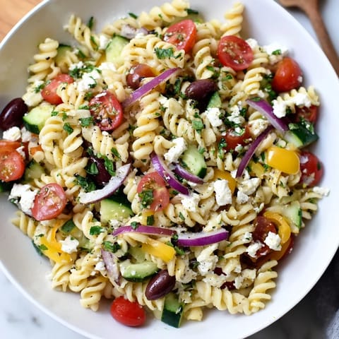 A colorful bowl of Lemon Pasta Salad, featuring feta cheese and fresh vegetables ready to be enjoyed.