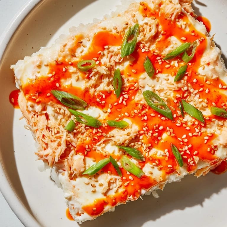 Golden, bubbly Creamy Salmon Sushi Bake, fresh from the oven, with sesame seeds and scallions.