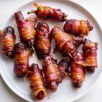 Crispy bacon wraps tender smokies in this image of 3-Ingredient Bacon-Wrapped Smokies, glistening with caramelized sugar.