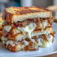 Gooey Gruyere cheese melts between tangy sourdough with sweet caramelized onions in this gourmet grilled cheese.