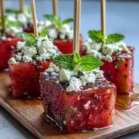Vibrant watermelon feta salad skewers with fresh mint, drizzled with olive oil and balsamic glaze, perfect for summer parties.  