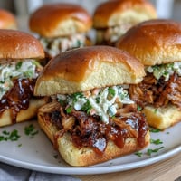 Mouthwatering BBQ pulled pork sliders with tangy coleslaw, served on soft buns for a baby shower party platter.  