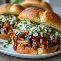 Tangy BBQ pulled jackfruit sandwiches loaded with creamy coleslaw on toasted buns.